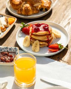 a plate of pancakes with fruit and a glass of juice at Kassandra Boutique Hotel in Oludeniz