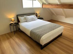 ein Schlafzimmer mit einem Bett mit zwei Tischen und einem Fenster in der Unterkunft Maleny-Montville Cottages #2, 2 bed with ocean views in Balmoral Ridge