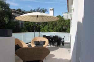 eine Terrasse mit einem Tisch, Stühlen und einem Sonnenschirm in der Unterkunft La Maison Blanche in Arles