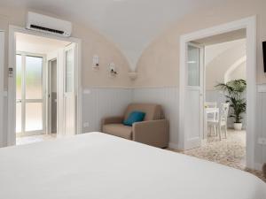 a white bedroom with a bed and a chair at EMMEhouse in Sant'Agnello