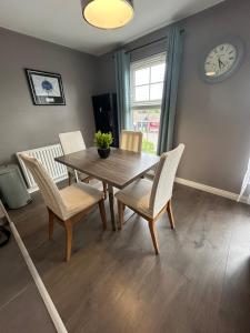 a dining room with a table and chairs and a clock at Saffron Loft, Belfast in Belfast