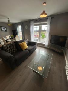 a living room with a couch and a glass coffee table at Saffron Loft, Belfast in Belfast