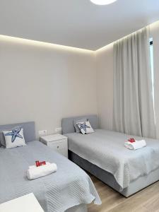 two twin beds in a room with white walls at Turquoise Pool Side Thymus Resort in Himare +110 photos