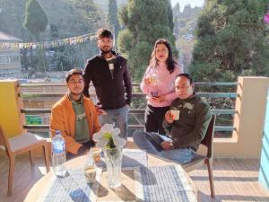 JālāpahārにあるCafe and Stayのバルコニーのテーブルの周りに座る人々