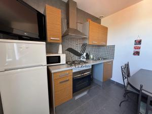 フラにあるARISTIDE 6 - Appartement idéalement situéの白い冷蔵庫とテーブルのあるキッチン