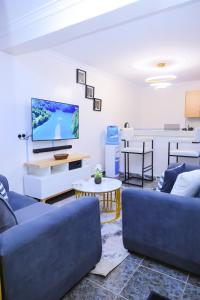 a living room with blue couches and a flat screen tv at 1 bedroom in Kamakis in Ruiru