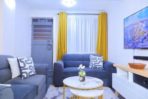 a living room with two blue couches and a table at 1 bedroom in Kamakis in Ruiru +4 photos