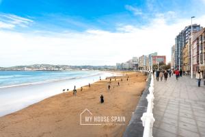 a group of people walking on the beach at Hotel Playa Poniente in Gijón
