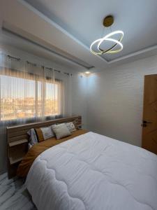 a bedroom with a large bed and a chandelier at Confort à Tanger, près gare & aéroport in Tangier