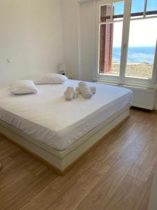 a bedroom with a bed with white sheets and windows at Artemi in Andros