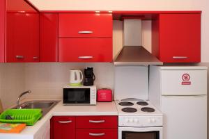 een kleine keuken met rode kasten en een magnetron bij Apartment Opatija 365, steps from the sea & city center, free street parking in Opatija