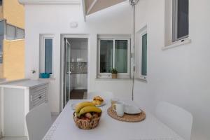 a white kitchen with a basket of fruit on a table at Refúgio Estrela do Mar in Quarteira +13 photos