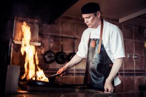 a man in a kitchen preparing food on a grill at Carlton George Hotel in Glasgow