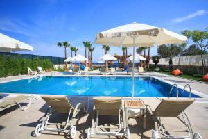 ein Schwimmbad mit Liegestühlen und Sonnenschirmen in der Unterkunft Esida Hotel in Küçükkuyu