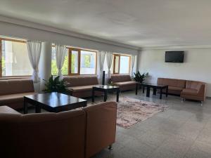 a living room with couches and tables and windows at Park Hotel Panorama in Tryavna