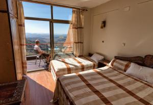 a man sitting in a chair in a hotel room with two beds at Panoramic View Hotel in Lalībela +101 photos