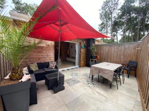 a patio with a red umbrella and a table at Nid chaleureux proche de l'océan in Lacanau