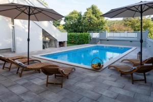 a pool with chairs and umbrellas on a patio at Holiday house with a swimming pool Zmijavci, Zagora - 24240 in Zmijavci