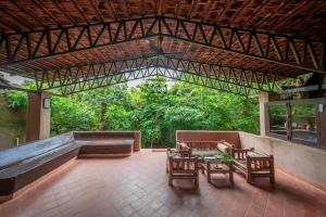 a patio with a table and chairs and a tub at Mahua Vann Pench in Khawāsa