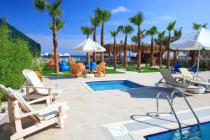 eine Terrasse mit Stühlen und ein Pool mit Palmen in der Unterkunft Esida Hotel in Küçükkuyu