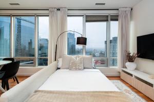 a large white bed in a room with large windows at Chic Downtown Apartment with City Views near Stanley Park in Vancouver