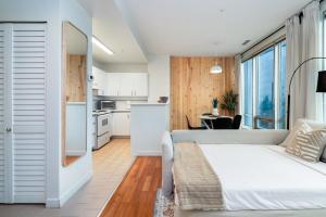 a bedroom with a white bed and a kitchen at Chic Downtown Apartment with City Views near Stanley Park in Vancouver