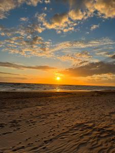 a sunset on the beach with footprints in the sand at Palanga Waterhouse in Kiauleikiai