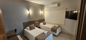 a hotel room with two beds and a television at Rede Andrade Center Premium in Rondonópolis