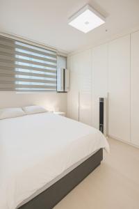 a white bedroom with a bed and a window at Glow House Seongsu A - Cozy and Brown Cat 외국인전용 in Seoul
