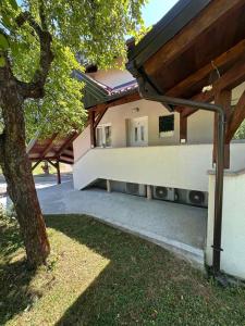 a building with a tree in front of it at Guest house Ema in Grabovac