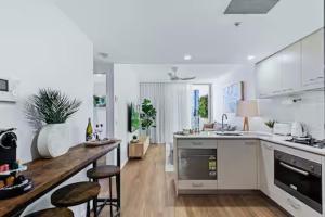 a white kitchen with a counter and stools in it at Elevate Brisbane City - Views, Pool, Sauna & Gym in Brisbane