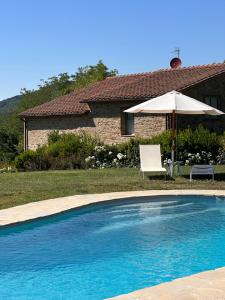 a swimming pool with an umbrella and a chair and an umbrella at Resort La noce di Francesca in Londa