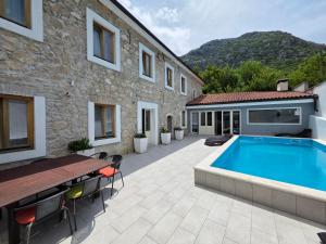 un patio con piscina junto a un edificio en STONE HOUSE with pool, en Tribalj