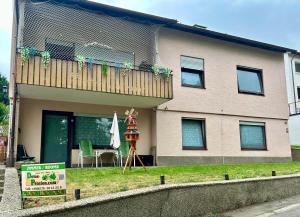 a house with a balcony with a table and an umbrella at Deine Pension, Double Room P1, 1-2 beds, 10qm, Check-in 4PM - 5AM in Creglingen
