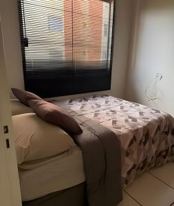 ein Bett in einem Schlafzimmer mit Fenster und Kissen in der Unterkunft Apto funcional e bem equipado in Maringá