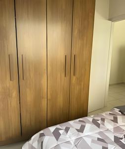 ein Schlafzimmer mit einem Bett und Holzschränken in der Unterkunft Apto funcional e bem equipado in Maringá
