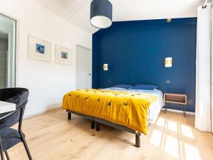 ein Schlafzimmer mit einer blauen Wand und einem Bett mit einer gelben Decke in der Unterkunft Maison de vacances avec jardin verdoyant à Loix - FR-1-835-25 in Loix