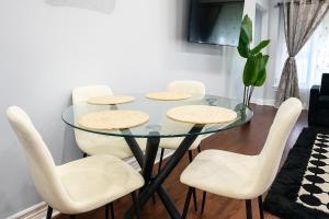a dining room with a glass table and white chairs at Newly Renovated 3BR North York Bungalow with Backyard Patio & Volleyball Set! Close to Rogers Stadium, TTC Subway Access, Perfect for Family Travel, Group Trips or Work Stays! in Toronto