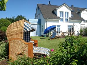 a yard with chairs and an umbrella and a house at Ferienhaus Am Felde in Groß Schwansee