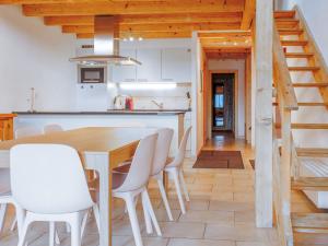 uma cozinha e sala de jantar com uma mesa de madeira e cadeiras brancas em Apartment Bietschorn 22 by Interhome em Nendaz mais 33 fotografias