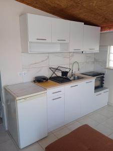 una cucina con mobili bianchi e un lavandino di Ελένη a Iraklitsa