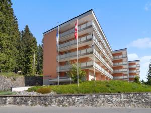 a building with two flags in front of it at Apartment Promenade Apt 407 by Interhome in Arosa