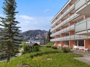 a building with a green lawn next to a tree at Apartment Promenade Apt 109 & Apt 110 by Interhome in Arosa