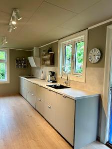 a kitchen with white cabinets and a clock on the wall at Hytte ved sjøen på Andabeløy in Flekkefjord