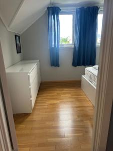 a bedroom with blue curtains and a bed and a window at Hytte ved sjøen på Andabeløy in Flekkefjord