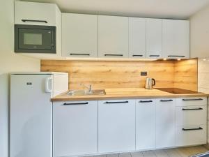 eine Küche mit weißen Schränken und einer Spüle in der Unterkunft Holiday Home Holiday Hill 45 by Interhome in Lauterwasser + 46 Fotos