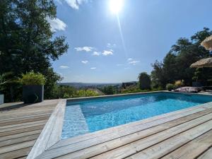a swimming pool on a wooden deck with a view at Brive, La Villa Bellevue in Buissou