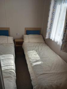two twin beds in a room with a window at Walnut 65 - Porthcawl in Newton