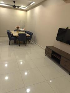 a dining room with a table and chairs and a flat screen tv at MM HomeStay 82 in Kamunting