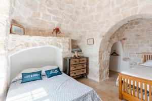 ein Schlafzimmer mit einem Bett und einer Steinwand in der Unterkunft Casa Sordella in San Michele Salentino + 75 Fotos